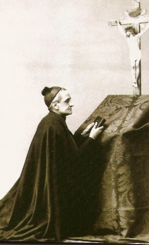 El Venerable en oración ante un Crucifijo.