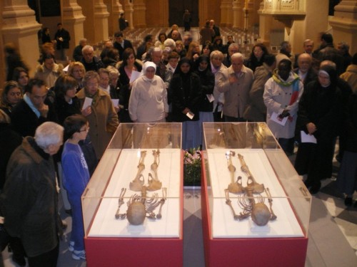 Un grupo de visitantes contempla los esqueletos recuperados y reconstruidos de los Santos. Catedral de Reggio Emilia, Italia.