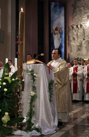 Diácono cantando en Pregón Pascual ante el Cirio Pascual.
